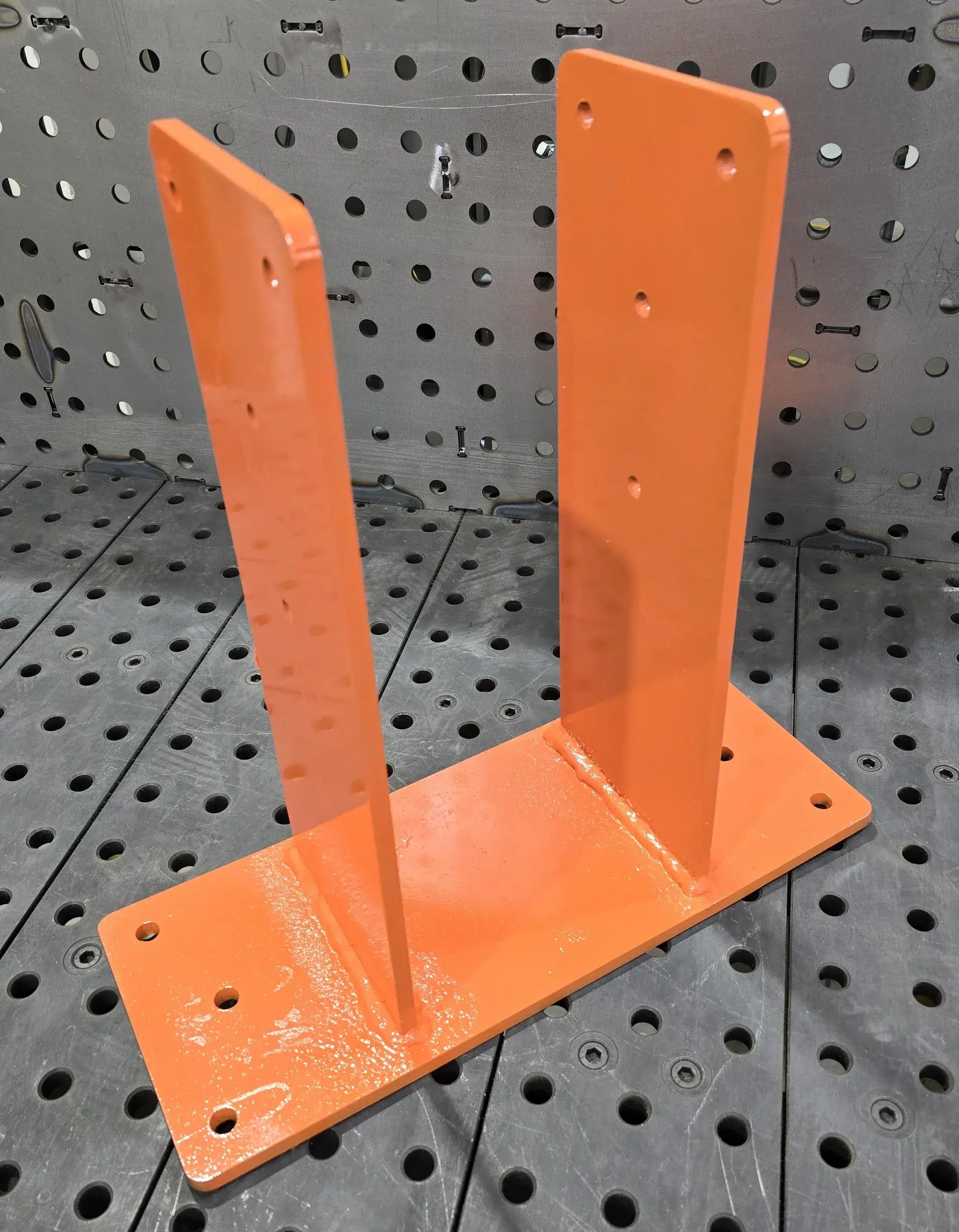 Orange welded steel U-bracket on perforated metal