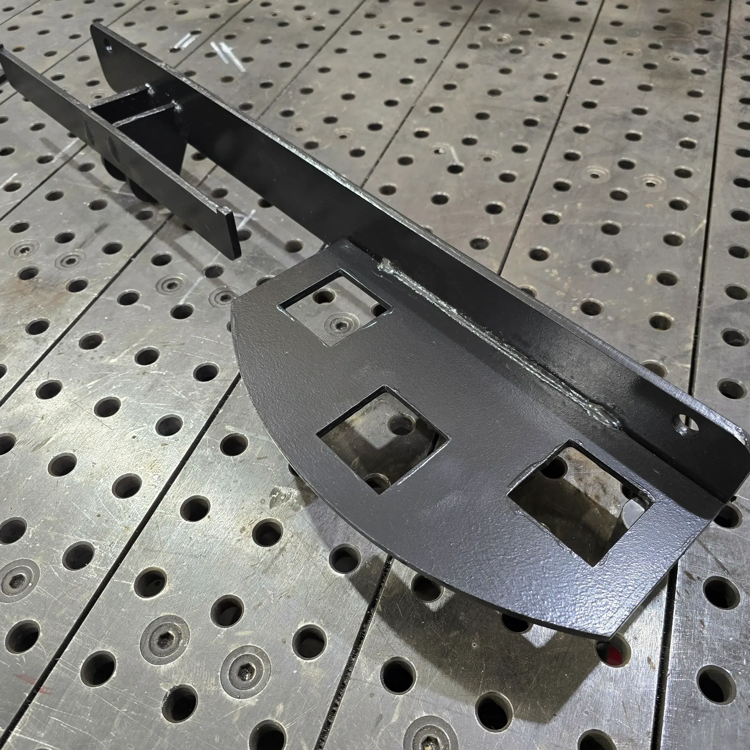 Black metal mounting bracket on perforated table