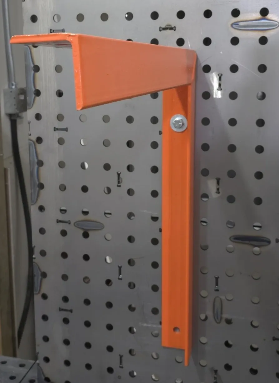 Orange L-shaped metal shelf bracket on pegboard
